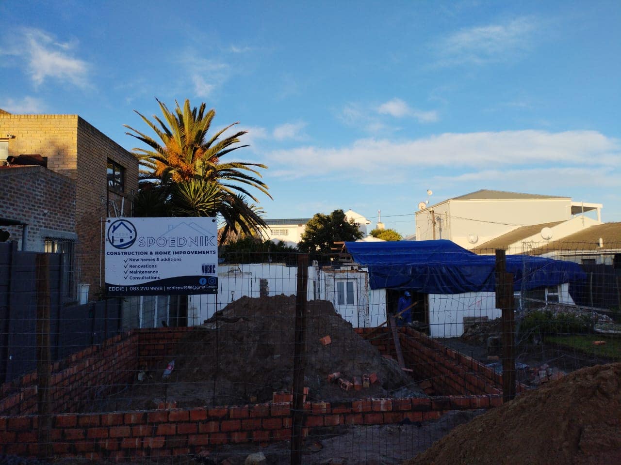 Spoednik Construction site board on a live Cape Town building site listing new homes, renovations, maintenance and consultations