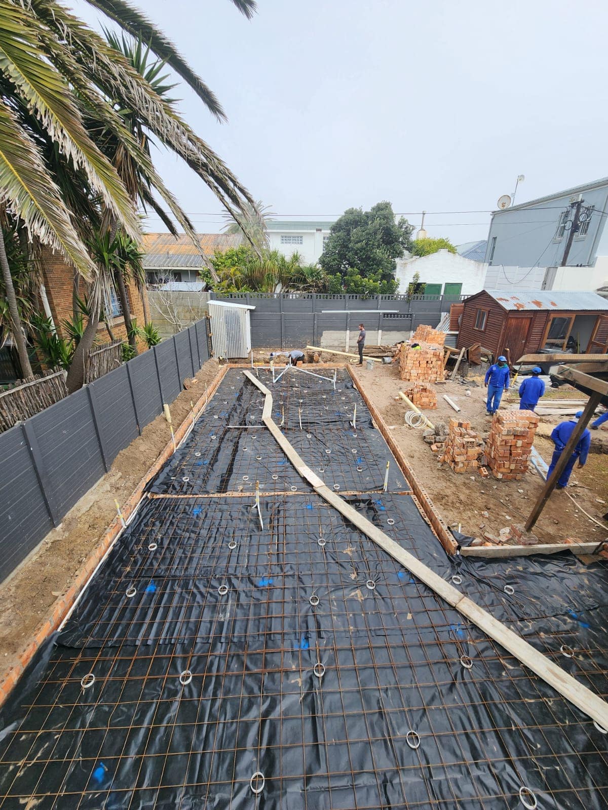 Damp-proof membrane laid across the footprint with reinforcement mesh on spacers above it
