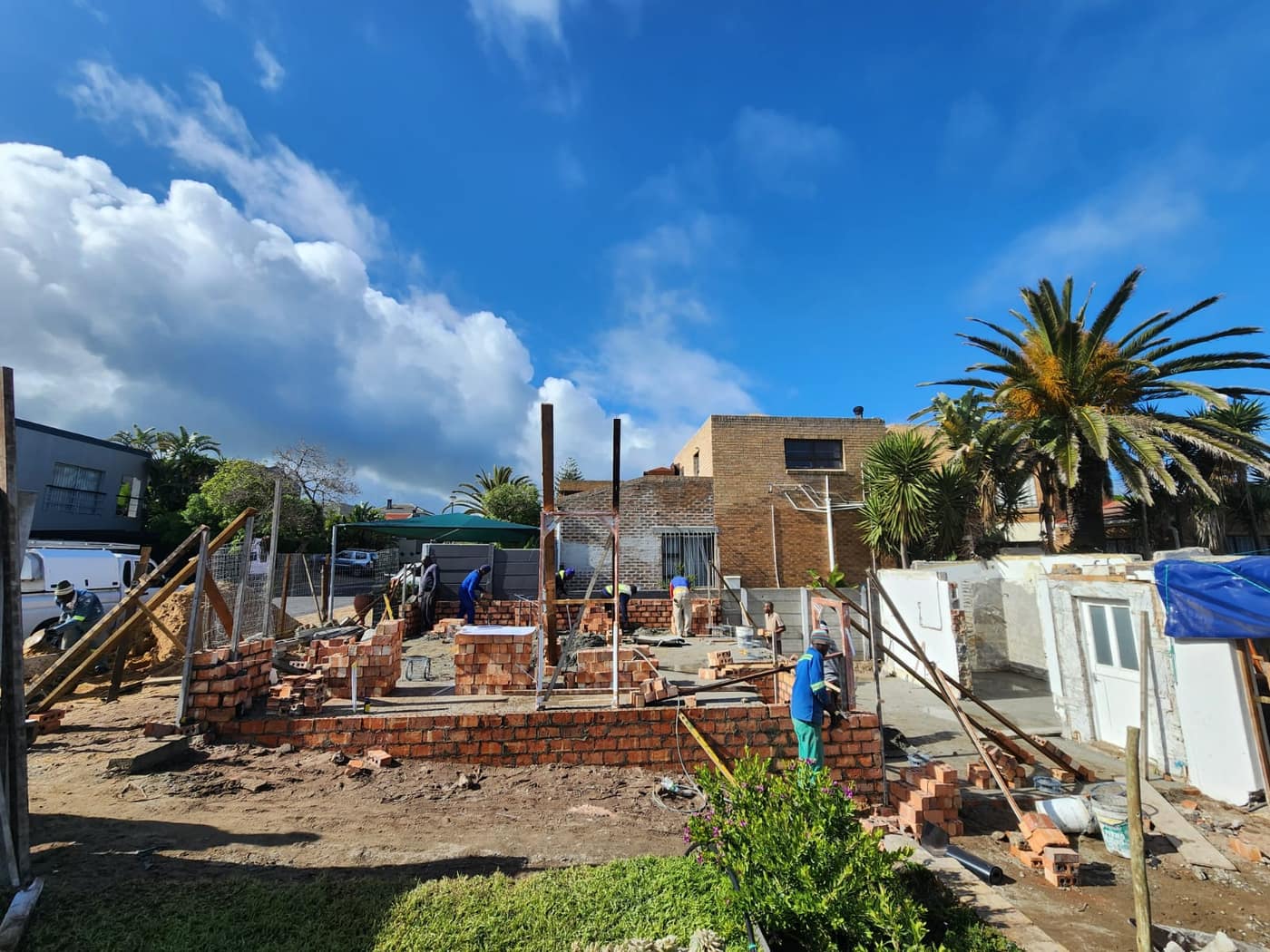 Bricklayers building the new walls up off the slab on a clear day