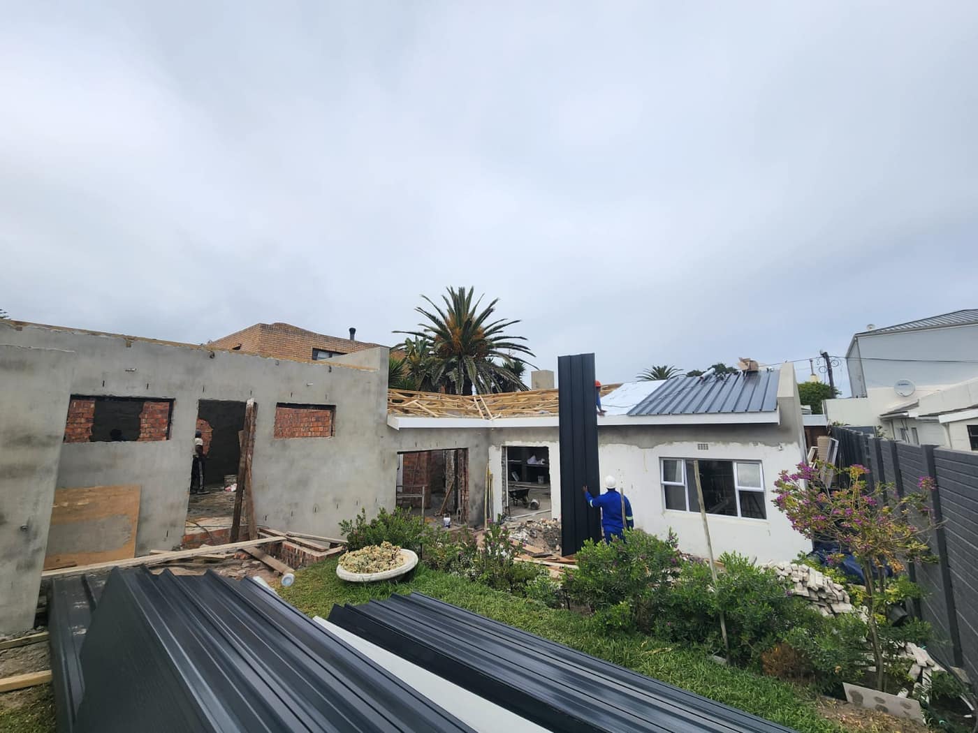 Standing-seam metal roof sheeting going on over new roof carpentry