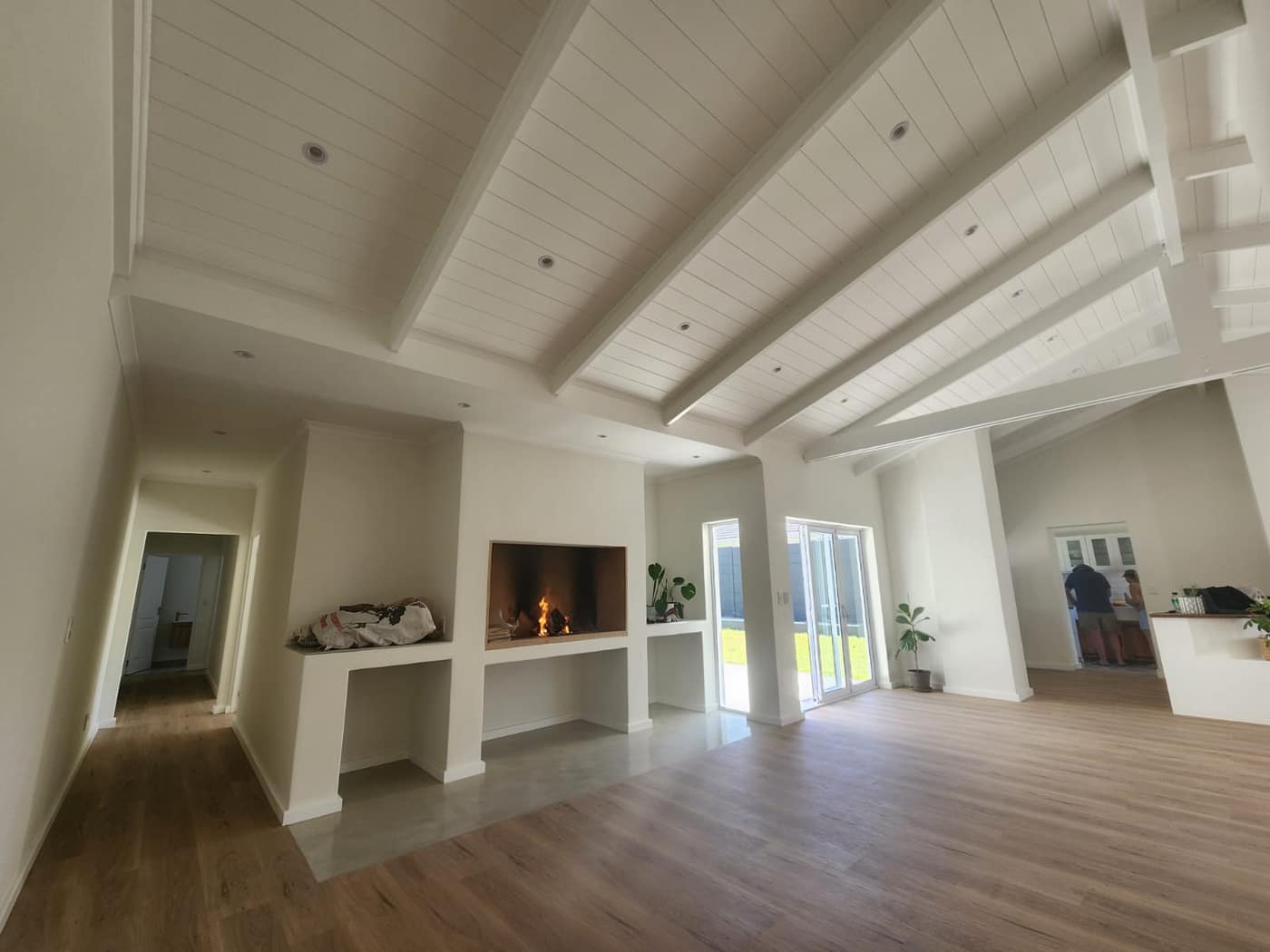 The finished open-plan living room with a lit fireplace and vaulted beamed ceiling