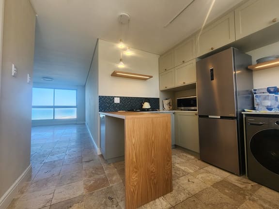 Compact coastal kitchen with a timber island and a sea view
