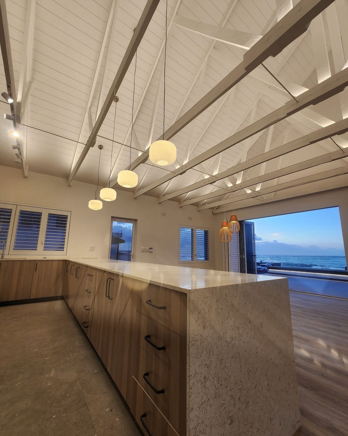 Completed coastal kitchen beneath a vaulted truss ceiling